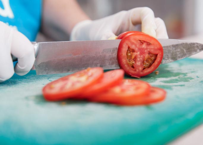 knife chopping tomato in swara kitchen