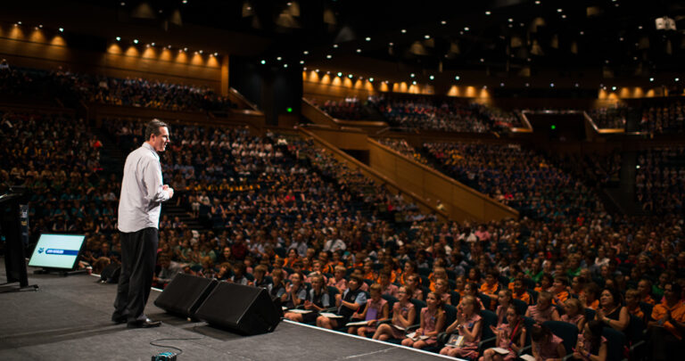 Lorin Nicholson OAM on stage presenting at large indoor event